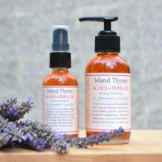 Two amber bottles of Aches & Pains Oil with pump tops sit in front of lavender sprigs. The labels highlight ingredients such as Arnica Montana, St. Johns Wort, and Lavender.
