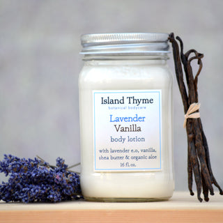 A jar of Lavender Vanilla Lotion rests on a surface, beside vanilla beans and lavender. Its label notes natural ingredients including shea butter, organic aloe vera, and the 16 fl. oz. size.