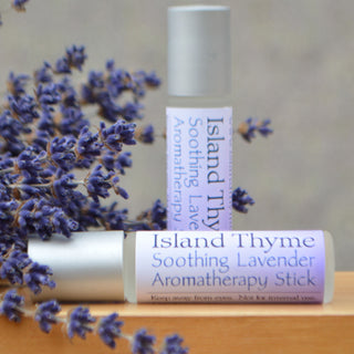 Two Soothing Lavender Sticks on a wooden surface—one upright, one lying down next to lavender flowers—create a calming atmosphere with the gentle scent of pure Lavender essential oil.
