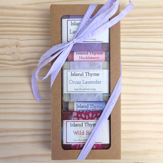 The Floral Gift Box features five Island Thyme handcrafted soaps in assorted floral scents, tied with a light purple ribbon and displayed on a light wooden surface.