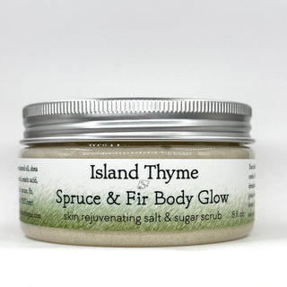 An 8 oz jar of Spruce & Fir Body Glow Salt & Sugar Scrub, a moisturizing and exfoliating body scrub with a silver lid and white label that blends salt and sugar to rejuvenate skin for a radiant glow.