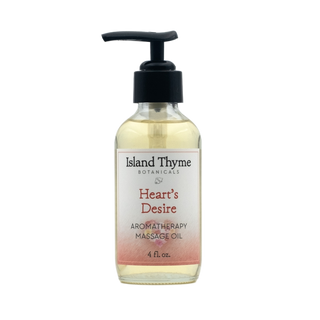 A clear bottle of Heart's Desire Aromatherapy Massage Oil with a black pump dispenser holds 4 fl oz, infused with essential oils and natural moisturizer, shown against a plain white background.