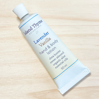 A 50 ml tube of Lavender Vanilla Lotion, featuring shea butter, sweet almond oil, organic aloe vera, and essential oils, is lying on a light wooden surface.