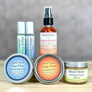 The Remedies & Soothers Deluxe set, featuring natural options for aches, pains, and healing, is artfully arranged on a wooden surface with a soft-focus background.